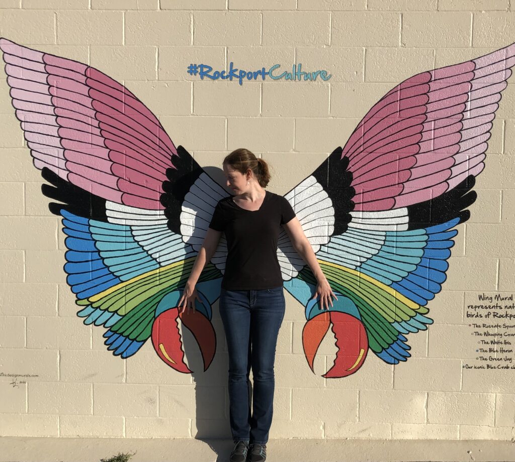 Portrait of the author, Lynne, in front of a butterfly mural.